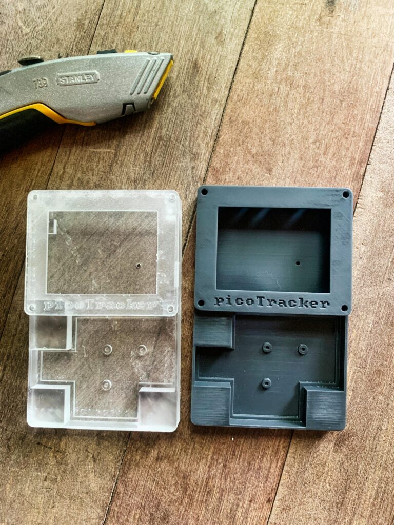 pexels photo 32764504 32764504 Display of transparent and black 3D printed PicoTracker cases next to a utility knife on a wooden surface.